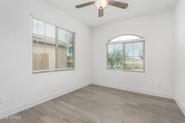 an empty room with wooden floor chandelier and windows