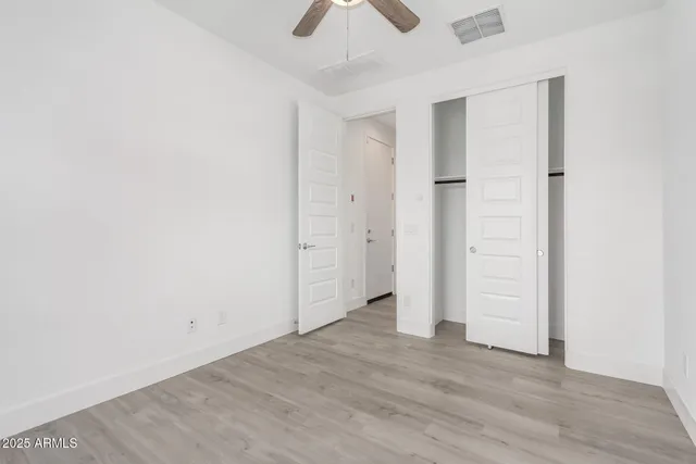 an empty room with closet and a chandelier fan