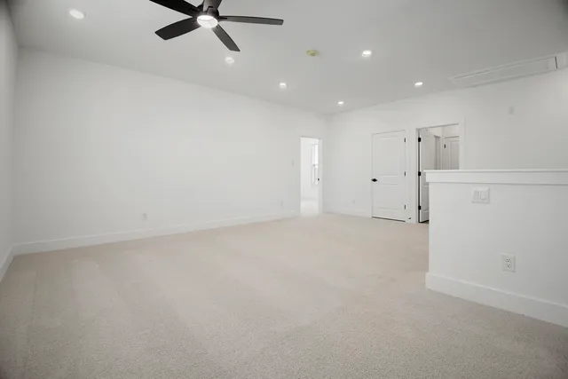 an empty room with windows and ceiling fan
