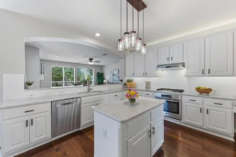 a kitchen with a sink a stove cabinets and wooden floor