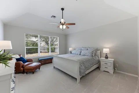 a spacious bedroom with a bed a couch and a chandelier