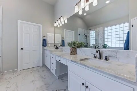 a bathroom with double vanity sinks a vanity a lamp and a mirror