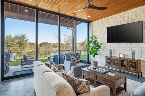 a living room with furniture a flat screen tv and a floor to ceiling window
