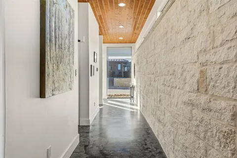 a view of a hallway with wooden floor and a bathroom