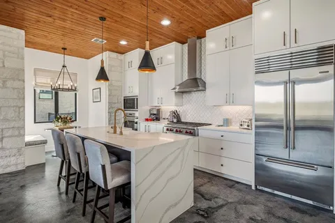 a kitchen with stainless steel appliances kitchen island granite countertop a sink a stove and cabinets