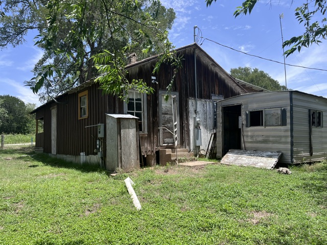 A rustic structure with weathered wood siding stands amidst a serene, rural escape.