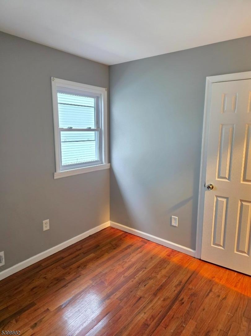 97 Goodwin Avenue Newark, NJ 07112 - Photo 13 of 20 an empty room with wooden floor and windows