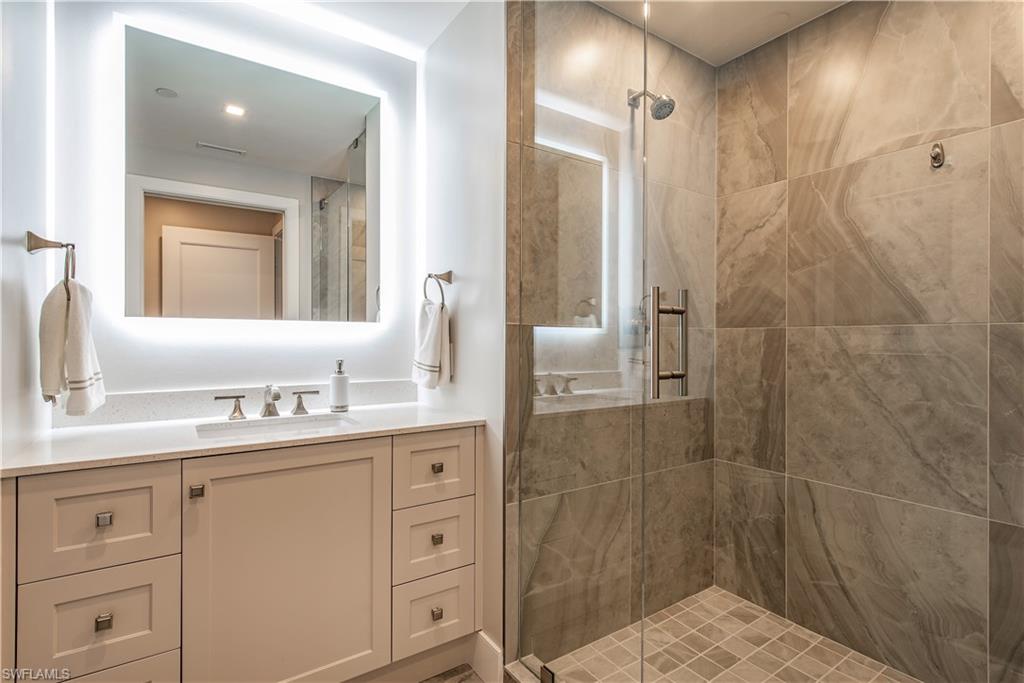 13915 Old Coast Road, Unit 602 Naples, FL 34110 - Photo 17 of 25 a bathroom with a shower sink and mirror