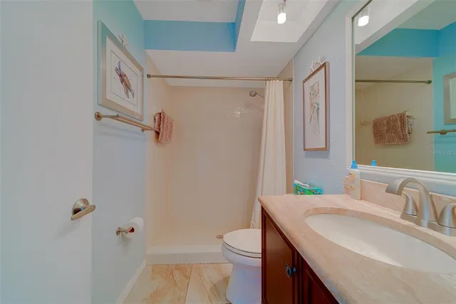 a bathroom with a granite countertop sink a toilet and shower