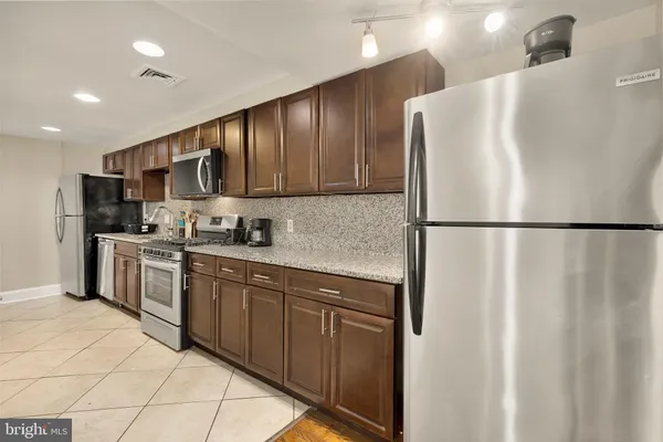 a kitchen with stainless steel appliances granite countertop a refrigerator a sink and a stove