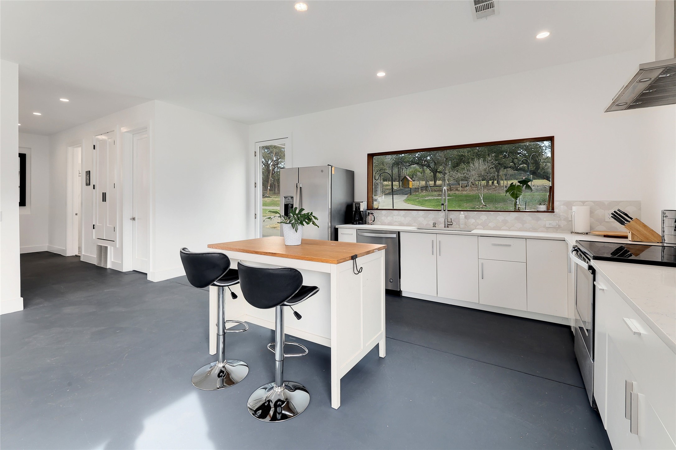 7001 Ranch Road 2222 Austin, TX 78730 - Photo 5 of 18 A sleek, contemporary kitchen with polished concrete floors and a wide picture window framing the natural landscape.