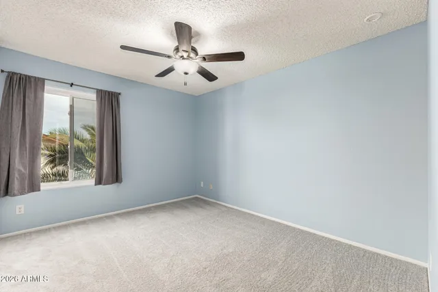 an empty room with a window and a fan