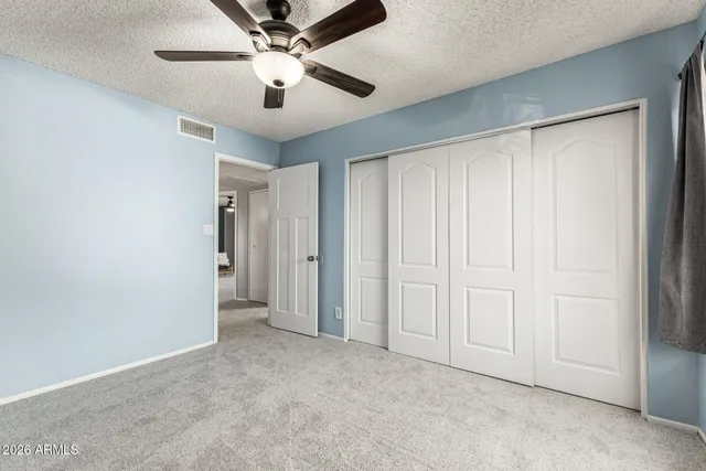 an empty room with windows and fan