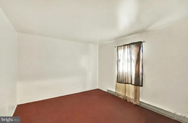 an empty room with window in back and closet