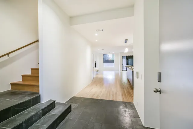 a view of a hallway with wooden floor and staircase