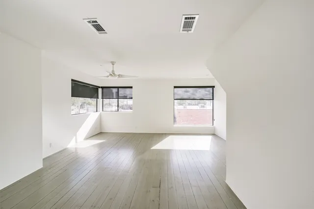 an empty room with wooden floor and windows