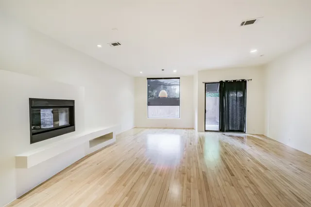 a view of an empty room with a window and wooden floor
