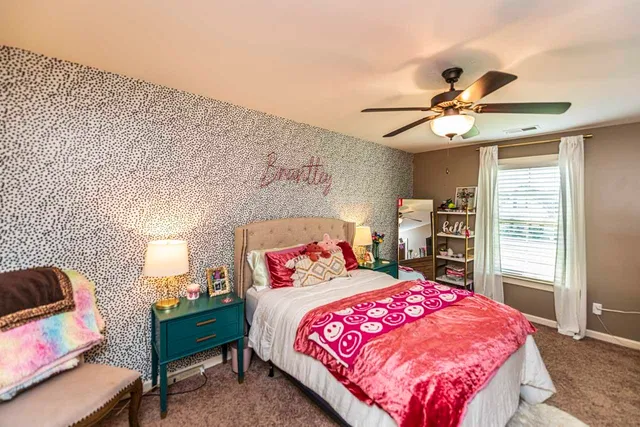 a bedroom with a bed a chandelier and pink walls