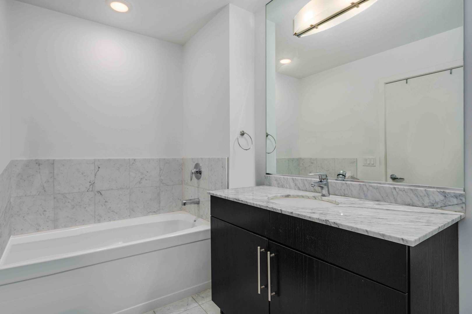 123 South Green Street, Unit 710B Chicago, IL 60607 - Photo 14 of 17 a bathroom with a granite countertop sink mirror and a bathtub