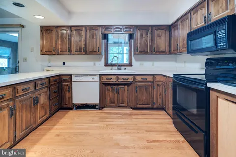 a kitchen with stainless steel appliances granite countertop a sink a stove top oven a refrigerator with wooden floors and cabinets