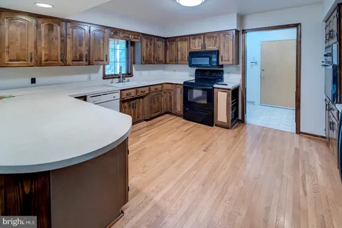 a kitchen with stainless steel appliances granite countertop wood cabinets a refrigerator and a sink