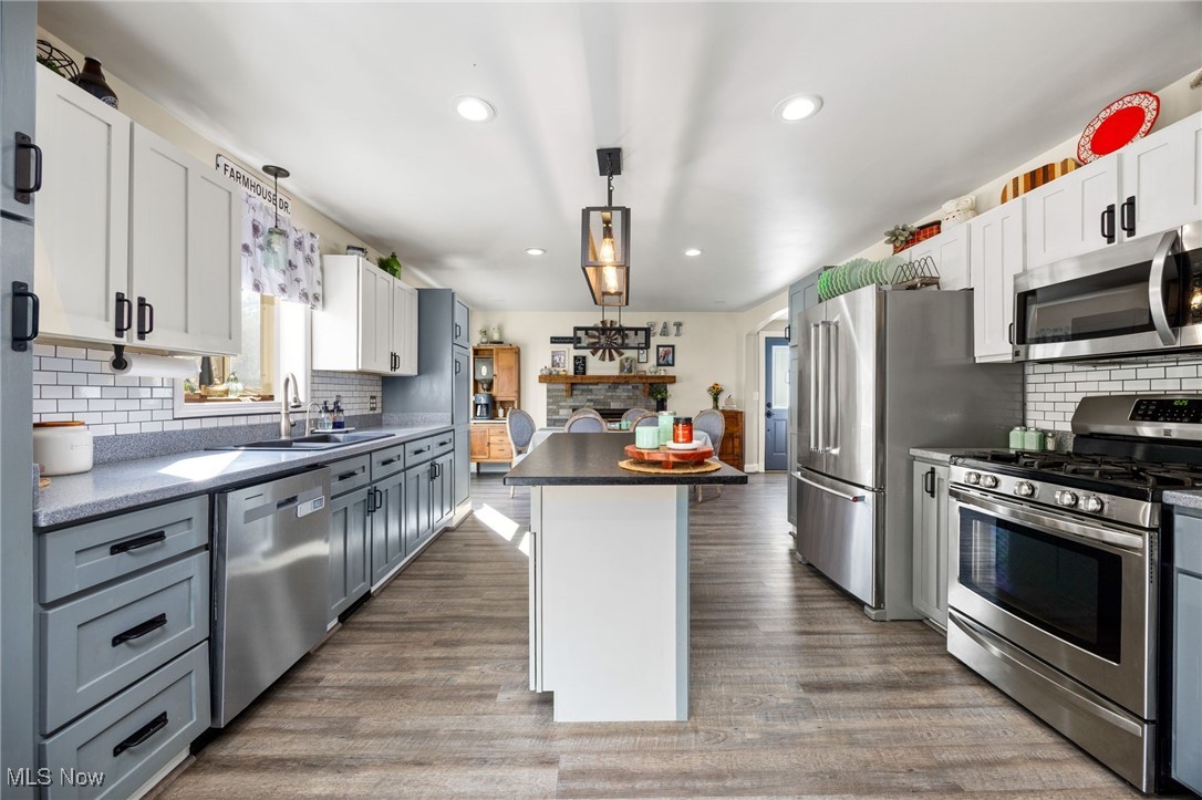 11827 Stratton Road West Salem, OH 44287 - Photo 21 of 47 Kitchen with backsplash, stainless steel appliances, hanging light fixtures, white cabinetry, and dark wood finished floors
