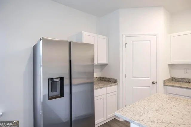 a kitchen with a refrigerator and white cabinets
