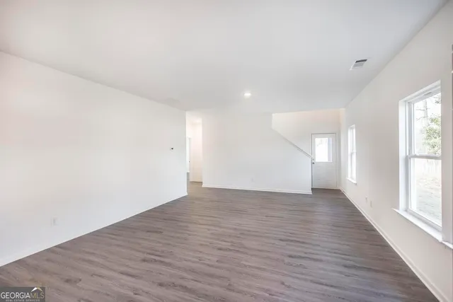 a view of an empty room with wooden floor and a window