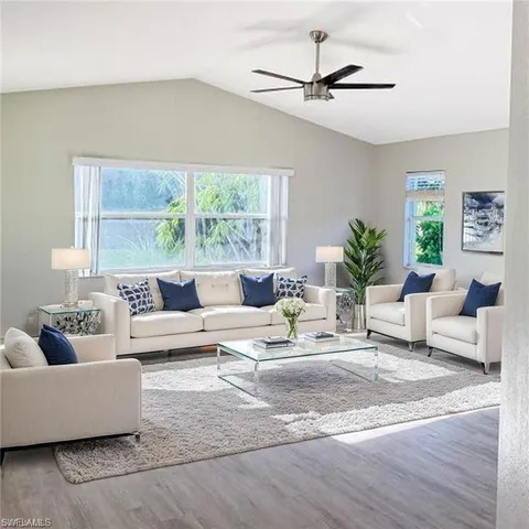 a living room with furniture a large window and a chandelier