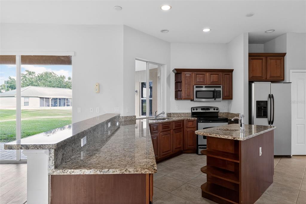 1216 Heavitree Court Sebring, FL 33876 - Photo 18 of 35 a large kitchen with kitchen island granite countertop a stove refrigerator and a sink