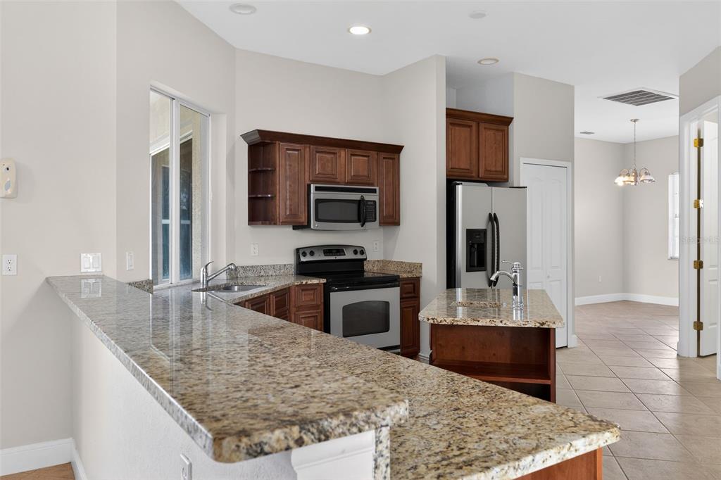1216 Heavitree Court Sebring, FL 33876 - Photo 19 of 35 a kitchen with kitchen island granite countertop a sink stove and refrigerator