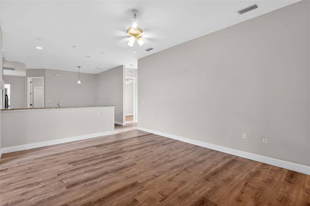1216 Heavitree Court Sebring, FL 33876 - Photo 7 of 35 a view of an empty room with wooden floor and a chandelier
