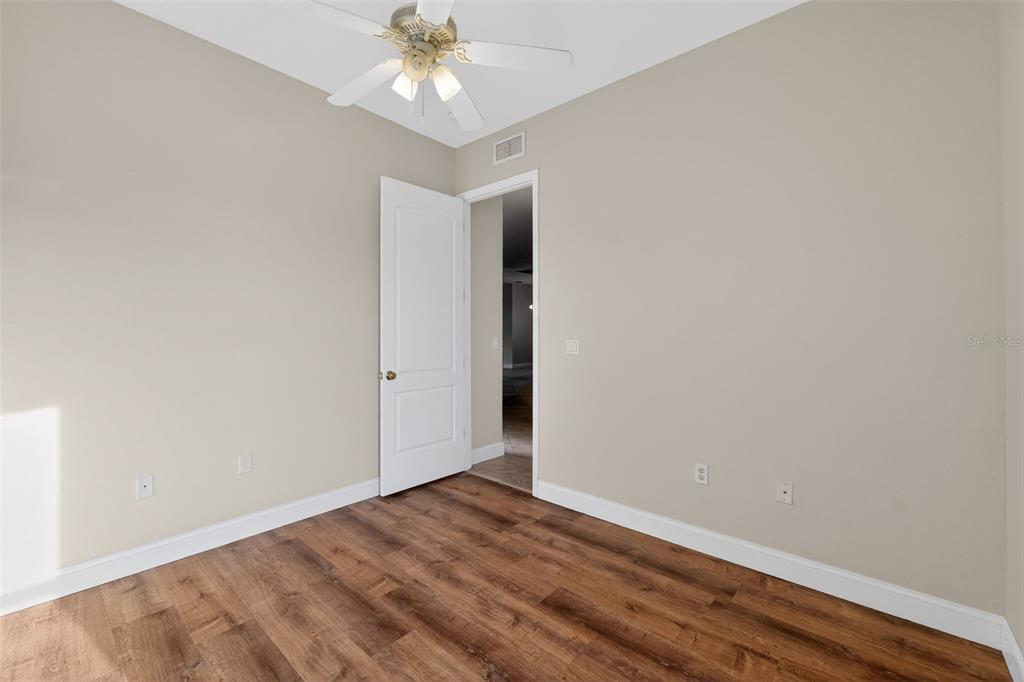 1216 Heavitree Court Sebring, FL 33876 - Photo 9 of 35 an empty room with wooden floor and fan
