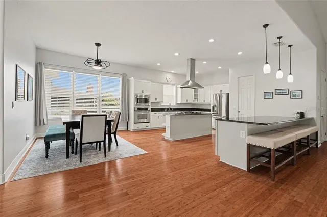 a living room with stainless steel appliances kitchen island granite countertop wooden floor and a dining table