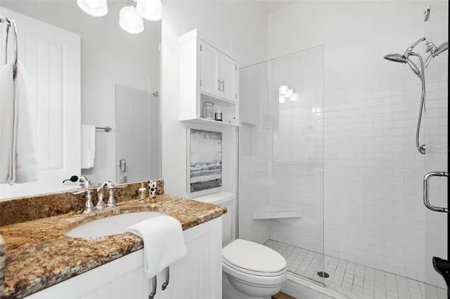 a bathroom with a granite countertop sink toilet and shower