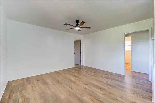 a view of empty room with a fan and wooden floor