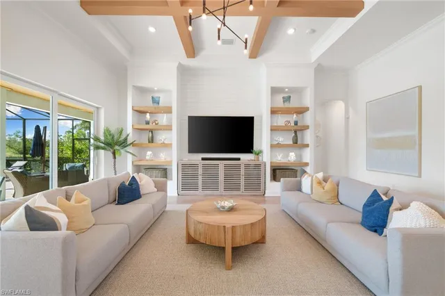 a living room with furniture a flat screen tv and a chandelier