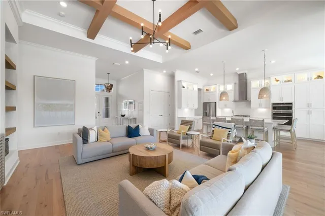 a living room with furniture kitchen view and a wooden floor