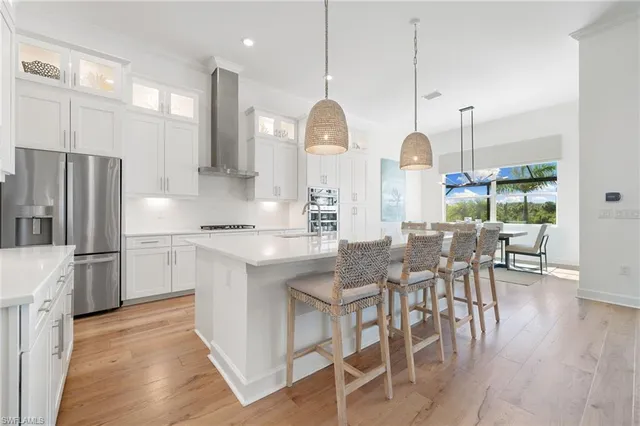 a kitchen with stainless steel appliances kitchen island granite countertop a table chairs and a sink