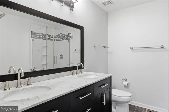 a bathroom with a granite countertop sink a toilet and a mirror