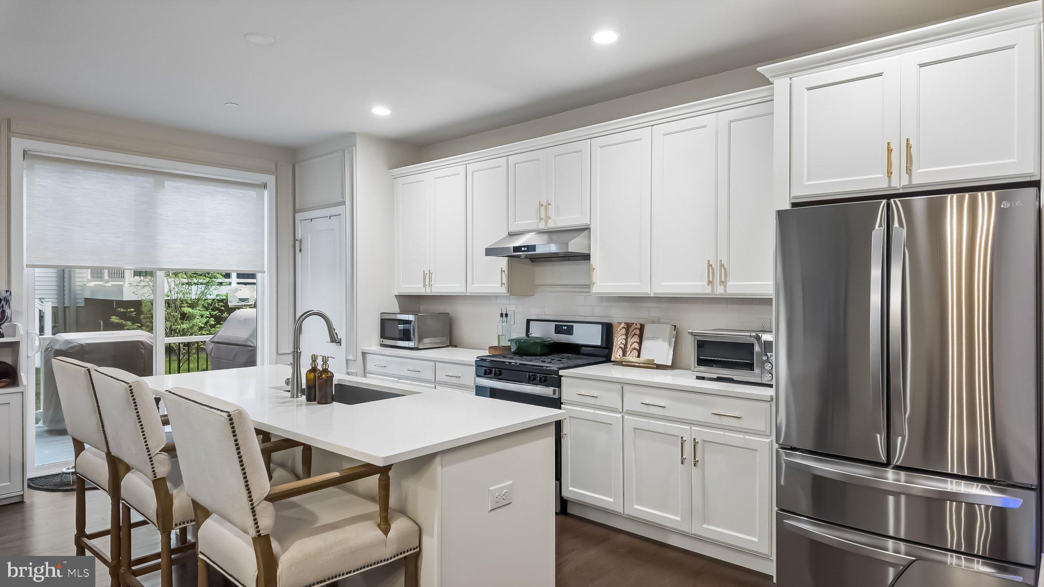257 Junction Road Media, PA 19063 - Photo 8 of 25 a kitchen with a refrigerator a stove a sink and white cabinets with wooden floor