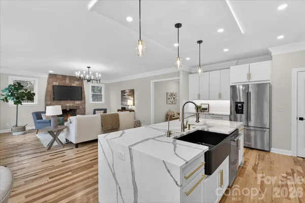 a large kitchen with kitchen island a refrigerator a stove a sink dishwasher a dining table and chairs with wooden floor