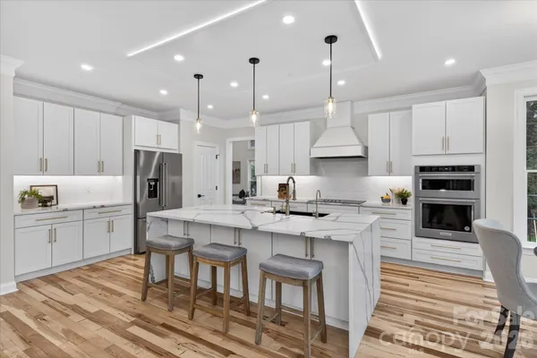 a kitchen with stainless steel appliances granite countertop a table chairs sink and stove top oven