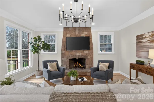 a living room with furniture a fireplace and a chandelier