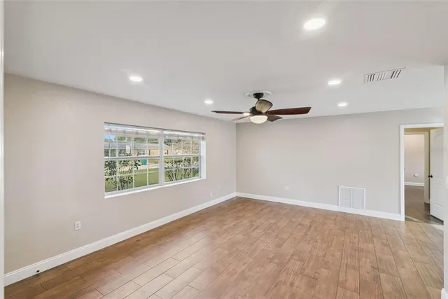 a view of empty room with wooden floor and ceiling fan