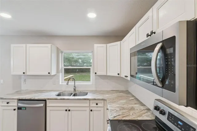 a view of a livingroom with a chandelier fan and wooden floor