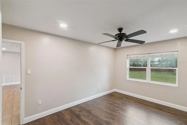 an empty room with a window and a fan