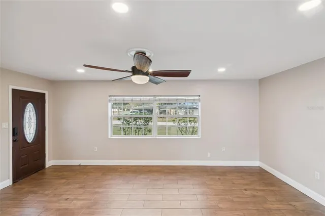 an empty room with wooden floor chandelier and windows
