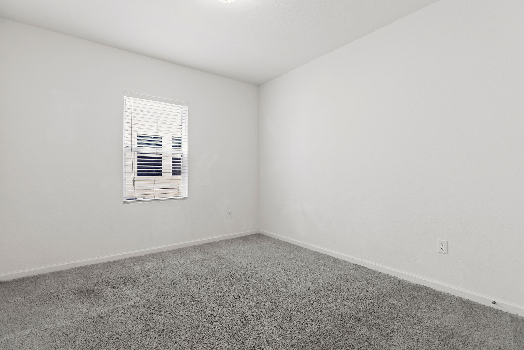 409 Line Of Fire Way Jarrell, TX 76537 - Photo 13 of 30 Room featuring light gray carpeting, white walls, single window with horizontal blinds, baseboard trim, and closet access.