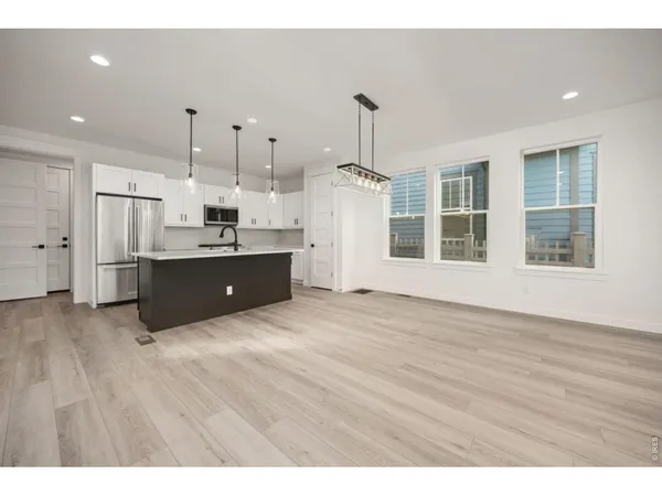 a open kitchen with stainless steel appliances granite countertop a refrigerator a sink dishwasher and a wooden floor